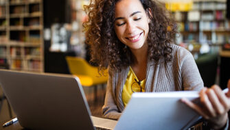 smiling woman with book and laptop