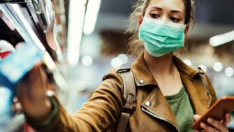 Woman wearing medical mask shopping in store with smart phone connected to store WiFi