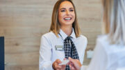 Smiling airport clerk handing ticket to passenger