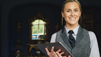 smiling hospitality worker holding a digital tablet