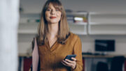 photo of smiling woman holding a cell phone in an office setting