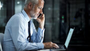business man using cell phone in front of laptop